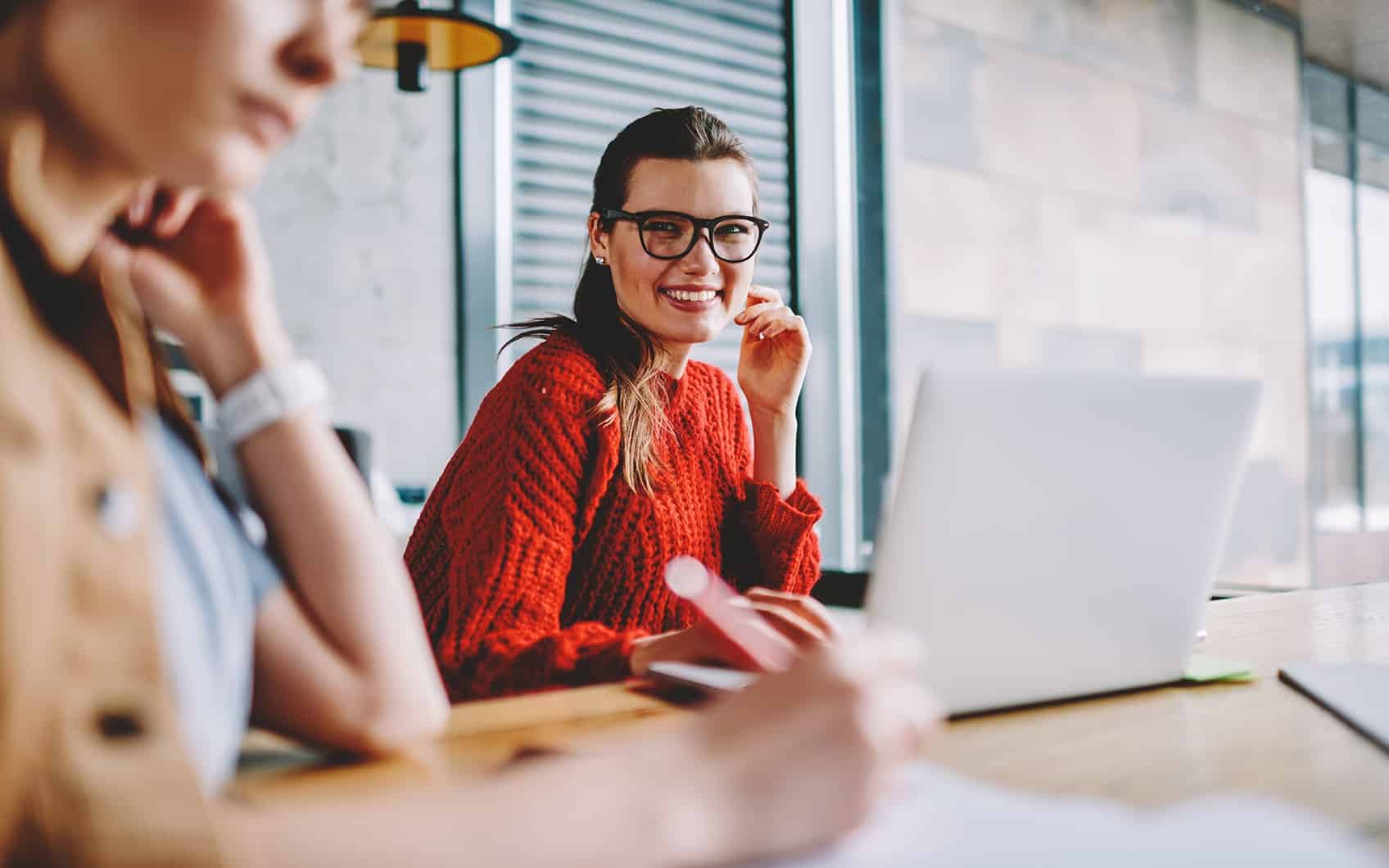 Frau lächelt an Schreibtisch mit Laptop