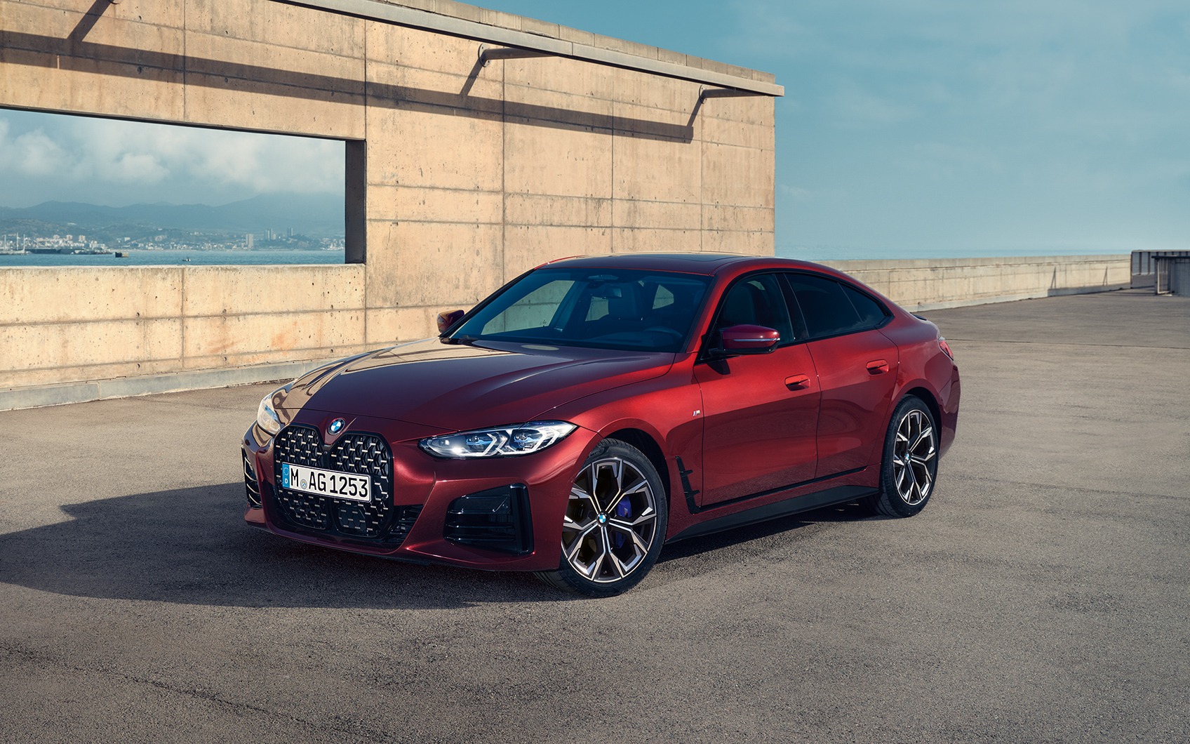 BMW 4er Gran Coupé rot vor Meer mit Stadt im Hintergrund