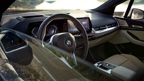 Blick durch die Seitenscheibe auf den Innenraum eines BMW 2er Active Tourer mit digitalem Cockpit und Automatikschaltung.