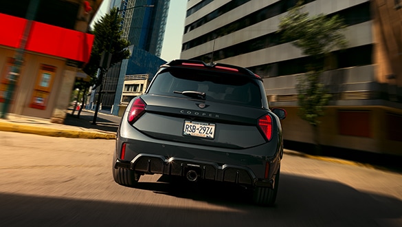 Heckansicht eines schwarzen MINI John Cooper Works  in Fahrt auf einer Straße in urbaner Umgebung