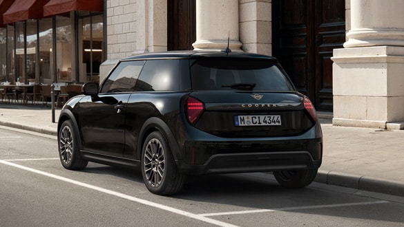 Heckansicht eines MINI Cooper Blackyard vor einem historischen Gebäude mit Säulen und Café im Hintergrund