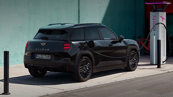 Heckansicht des MINI Aceman Blackyard angeschlossen an einer Ionity-Ladesäule am Straßenrand