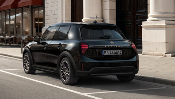 Heckansicht eines MINI Cooper 5-Türer Blackyard vor einem historischen Gebäude mit Säulen und Café im Hintergrund