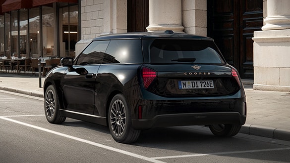 Heckansicht eines MINI Cooper Electric Blackyard vor einem historischen Gebäude mit Säulen und Café im Hintergrund