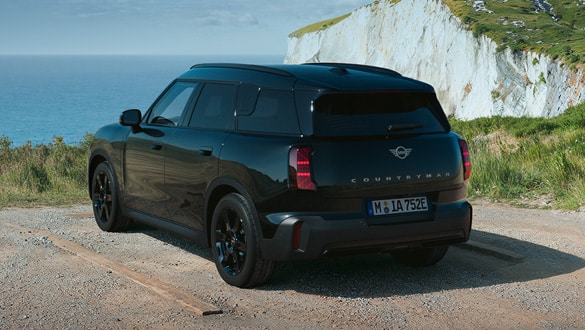 Heckansicht eines MINI Countryman Electric Blackyard auf einem Küstenweg mit Klippen und Meer im Hintergrund