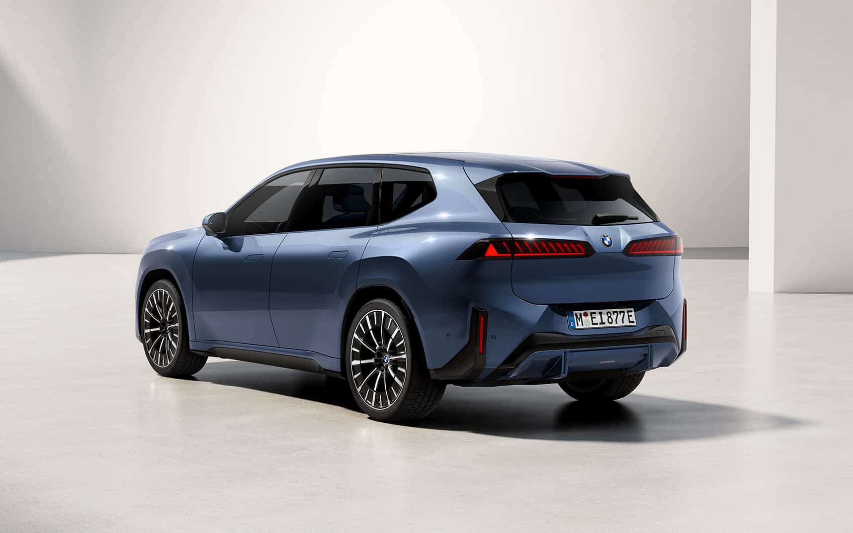 BMW iX3 in Blau von schräg hinten fotografiert in heller Studioumgebung.