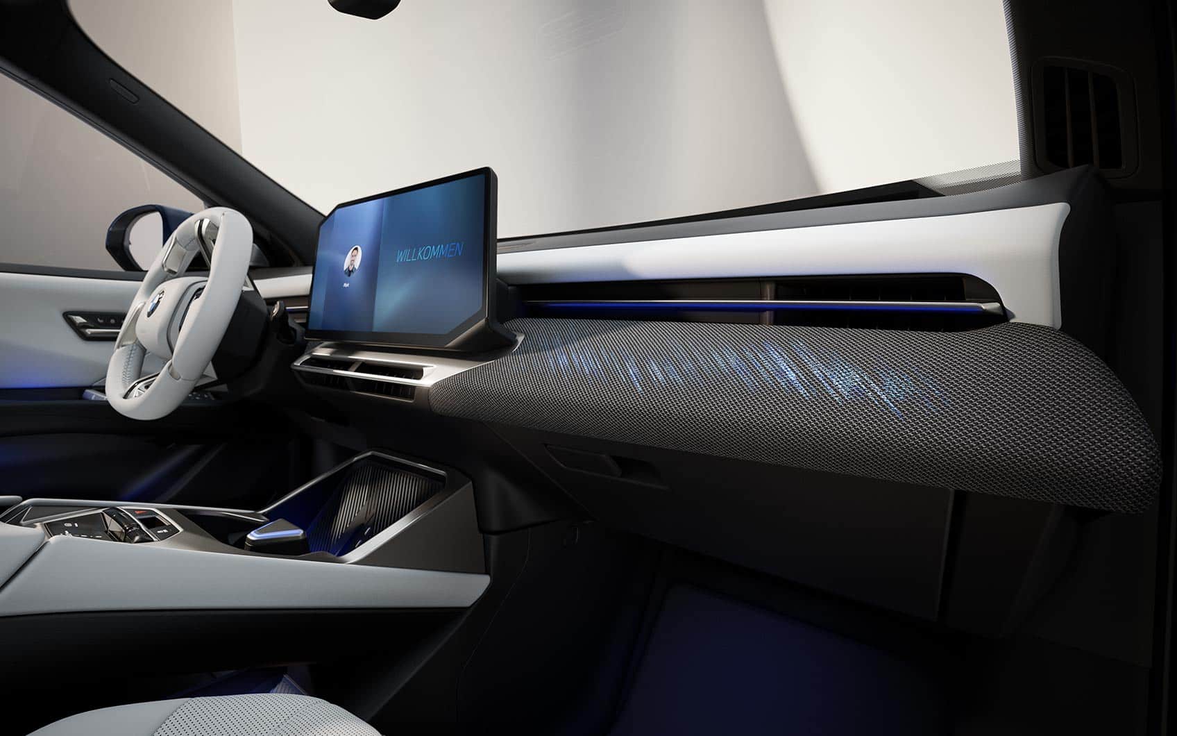 Vordere Innenraumansicht des BMW iX3 mit Display, Mittelkonsole und strukturiertem Armaturenbrett.