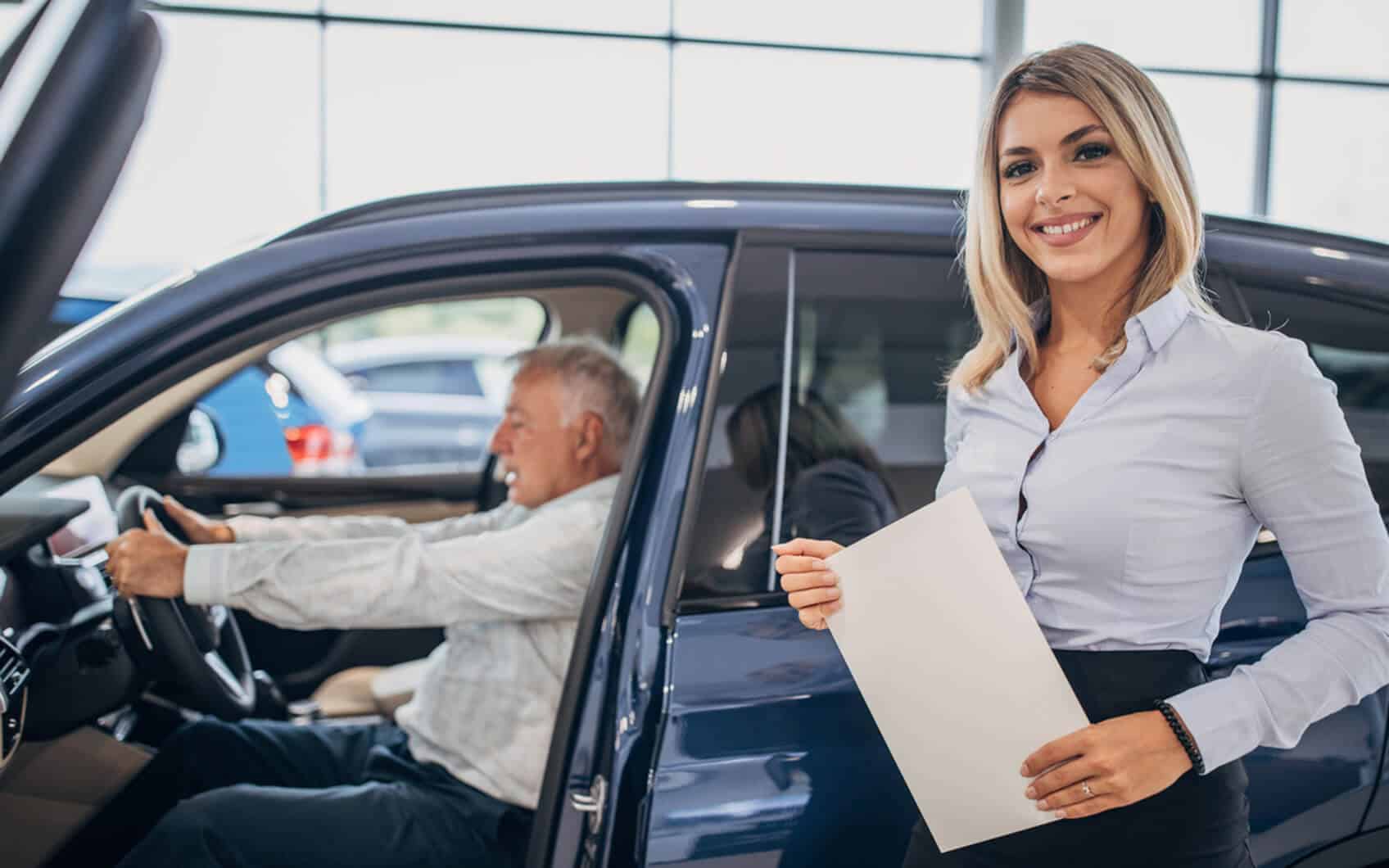 Automobilkauffrau berät einen Kunden bei der Fahrzeugbesichtigung im Autohaus.