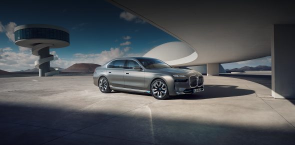 Silberner BMW i7 geparkt auf Betonfläche unter futuristischer Architektur