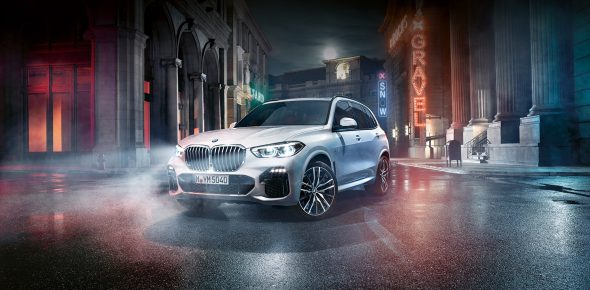 BMW X5 SUV auf nasser Straße, reflektierend, unter blau-orangefarbenem Licht, neonbeleuchtete Stadt im Hintergrund.