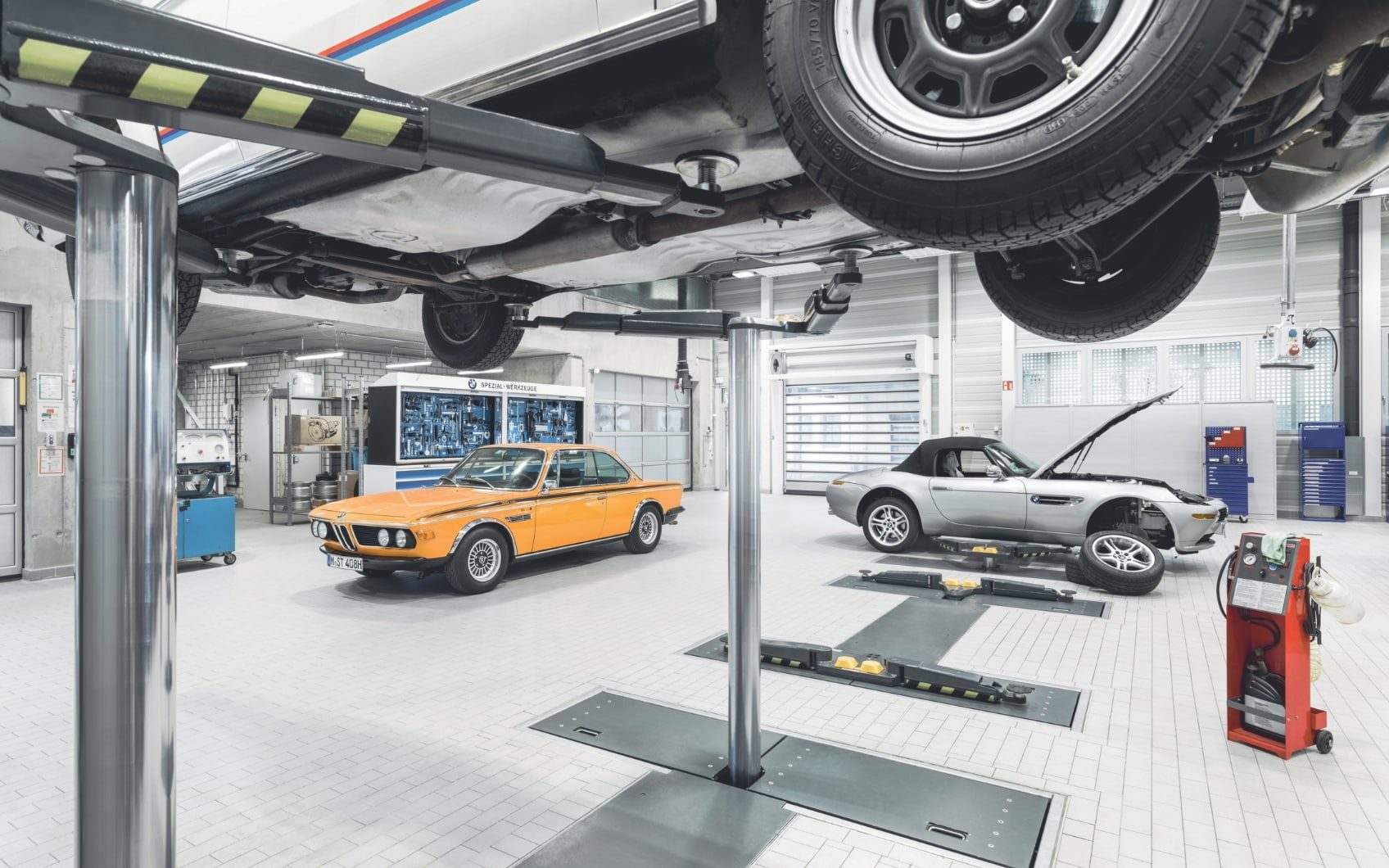 BMW-Werkstatt mit klassischen Fahrzeugen und Autos auf Hebebühnen.